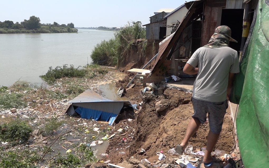 A man walks near a collapsed riverbank and houses along the Bassac river in Takhmao city, Kandal province on February 24, 2020. (Hy Chhay/VOD)