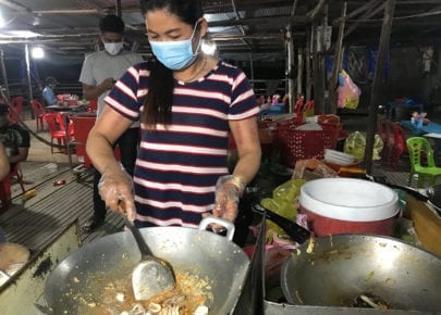 Chan Mach, 43, cooks while wearing a mask at her roadside restaurant in Takeo province in late March 2020.