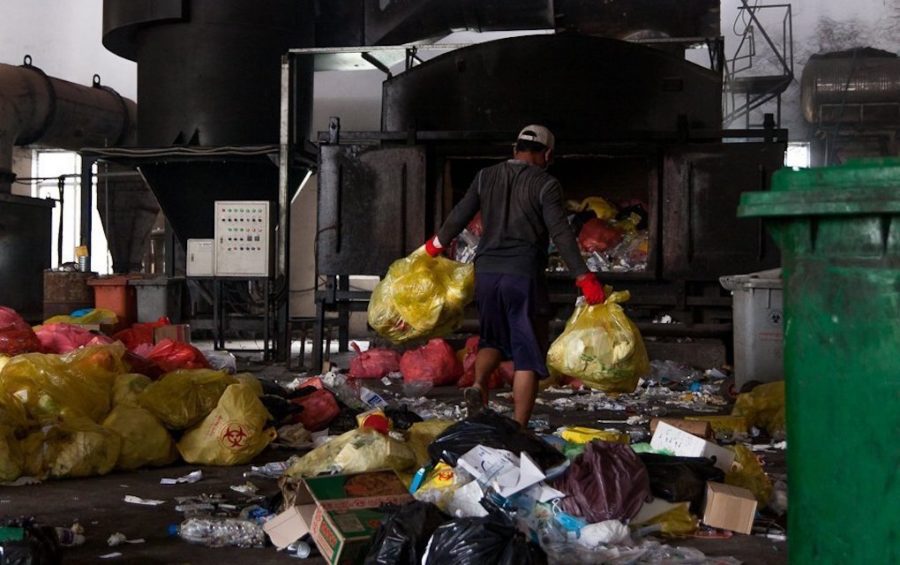 A Medical Waste Management Unit worker navigates the waste-strewn warehouse floor of the Dangkor landfill in Phnom Penh on April 9, 2020. (Gerald Flynn)
