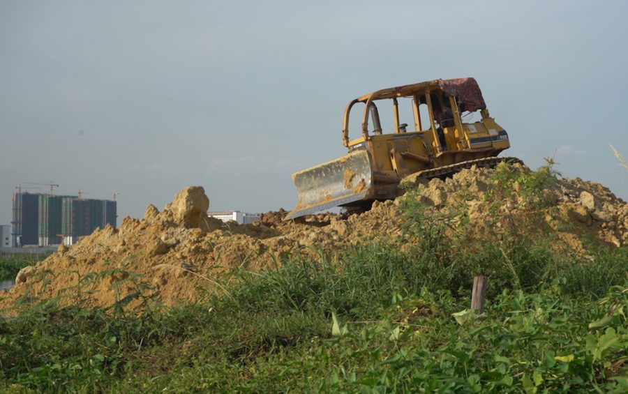 A bulldozer pushing sand and dirt into the wetlands, next to community farms in 2020 near Boeng Choeng Ek (STT)