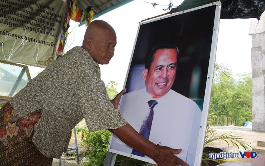 Kem Ley's mother Phork Se with a photo of the slain analyst near his unfinished stupa in Takeo province’s Tram Kak district. (Saut Sok Prathna/VOD)