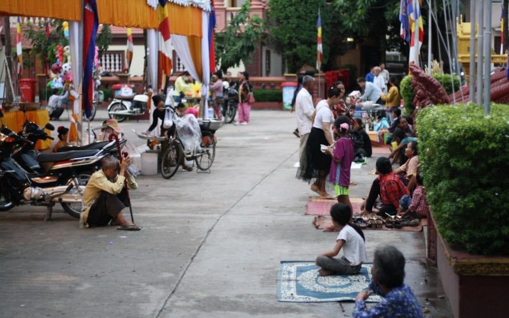 Few visitors walk past noodle vendors, shoe valets and beggars outside the main hall of Wat Sansam Kosal. (Michael Dickison/VOD)