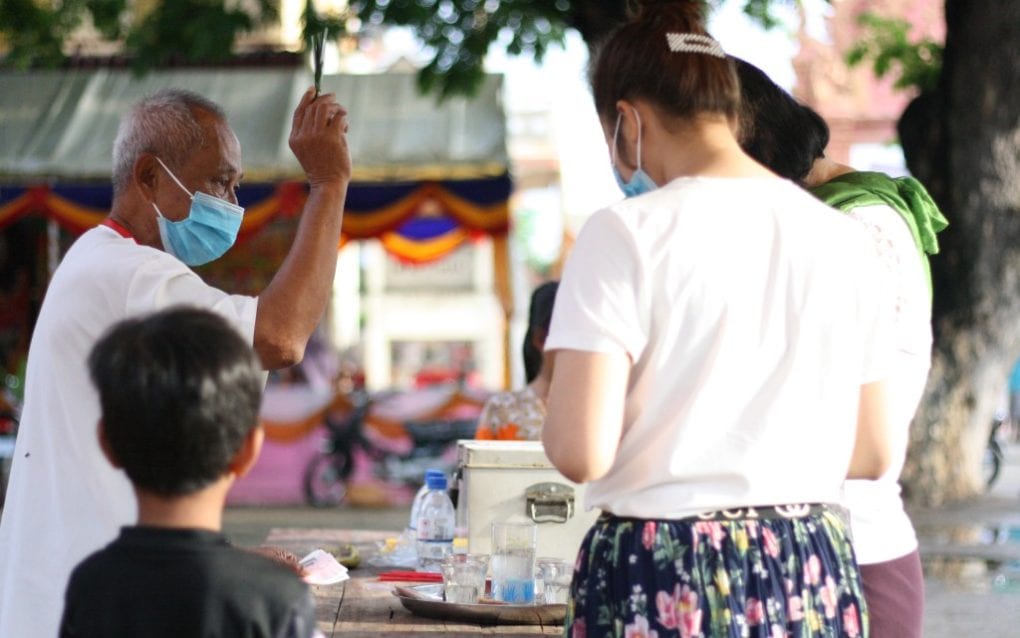 Lay priest Tith Ros, 79, performs a blessing ritual for pagoda visitors at Wat Nirouth on September 3, 2020. (Michael Dickison/VOD)