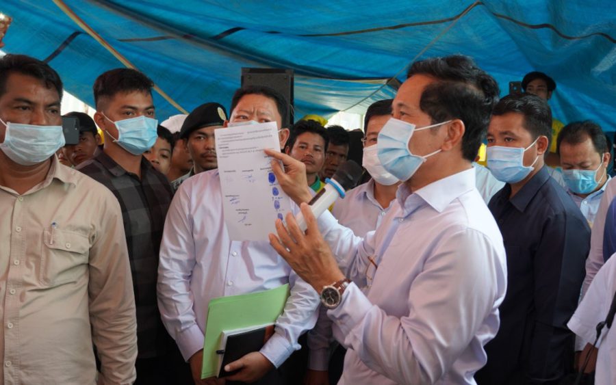 Phnom Penh governor Khuong Sreng holds up City Hall’s offer to guarantee striking garbage collectors’ benefits will not be lost amid restructuring, at Cintri’s truck garage in Daun Penh district on October 7, 2020. (Tran Techseng/VOD)