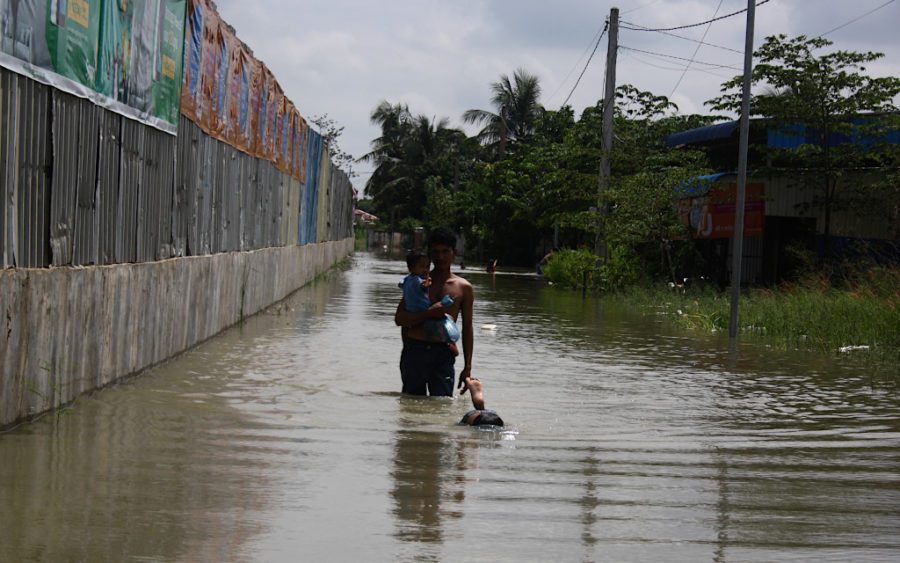 Lu Veasna, 32, carries his child through floodwaters in Phnom Penh’s Dangkao district on October 12, 2020. (Michael Dickison/VOD)