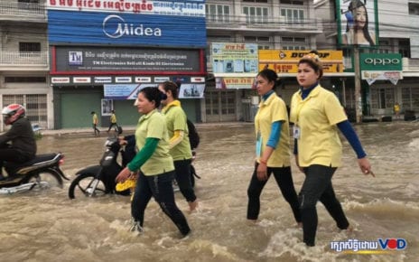 Workers wade through a flooded street in Phnom Penh on October 13, 2020. (Heng Vichet/VOD)