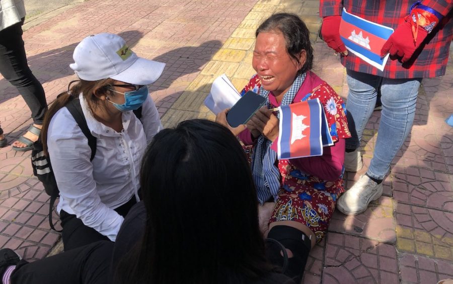 Demonstrator Sath Pha sits on the ground crying after being carried away from the Chinese Embassy in Phnom Penh by security guards following a protest across the street on October 23, 2020 (Matt Surrusco/VOD)