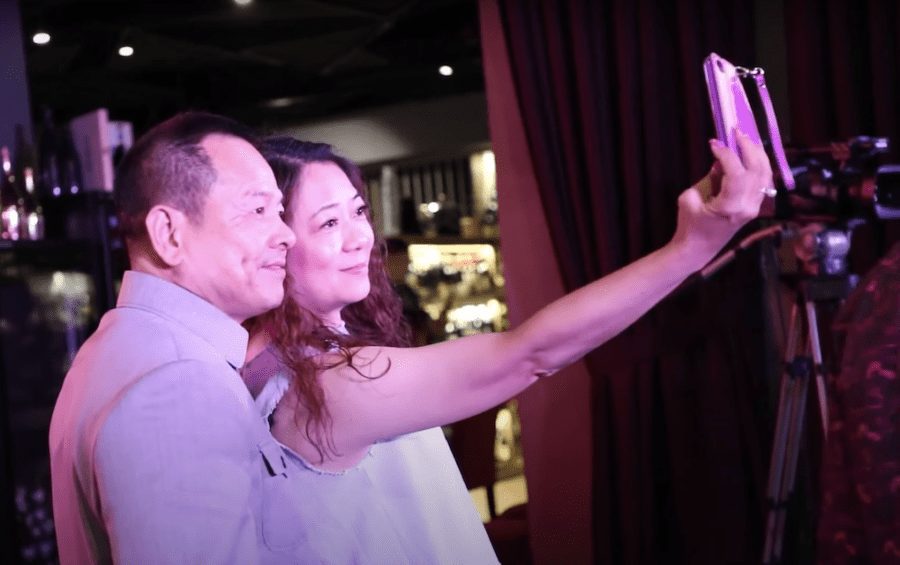 Former Macau crime boss Wan Kuok Koi, also known as “Broken Tooth,” takes a selfie with a woman at a ceremony in Kuala Lumpur in July 2018 marking the establishment of the World Hongmen History and Culture Association headquarters, in a screenshot from a promotional video.