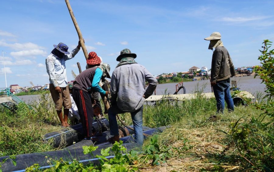 Men work to fix a pipe used to transport dredged sand along the Bassac river near Chak Angre Krom pagoda on December 16, 2020. (Tran Technseng/VOD)