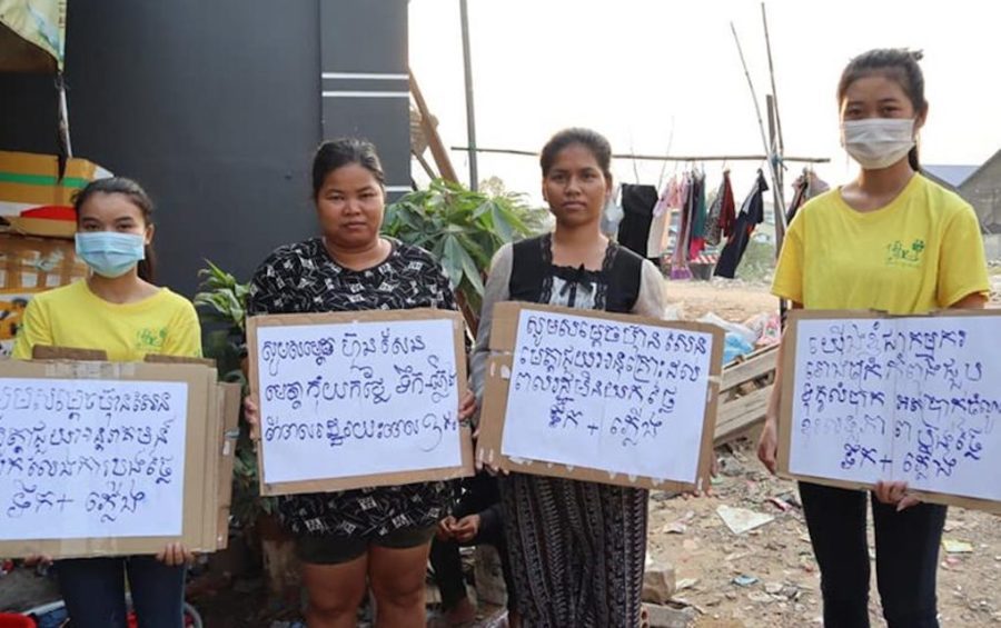 Two youth activists and two others hold signs calling for financial relief amid the Covid-19 pandemic. (Women’s Association for Society)