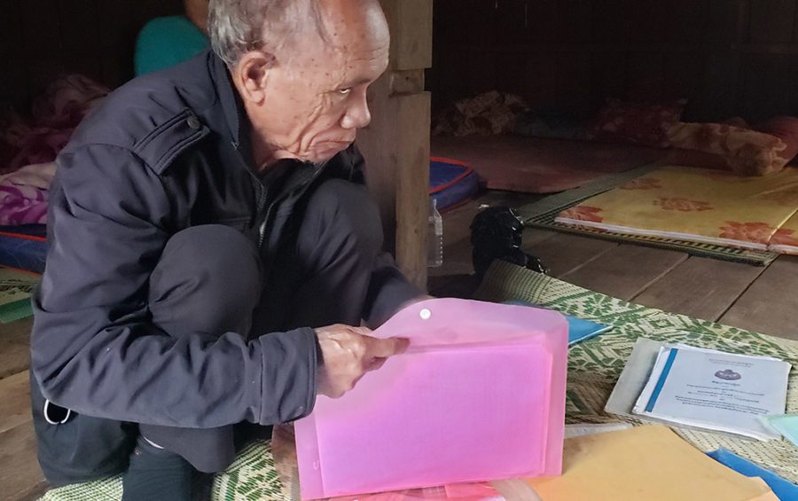 Pu Rang village community leader Nhak Srev opens up folders holding multiple complaints he filed and documentation from the village's communal land title application, in Mondulkiri province's O'Reang district on February 13, 2021. (Danielle Keeton-Olsen/VOD)