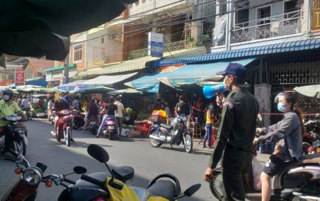 A guard talks into a loudspeaker as customers buy vegetables before a two-week market shutdown, near Phnom Penh's Olympic Market on April 24, 2021. (Danielle Keeton-Olsen/VOD)