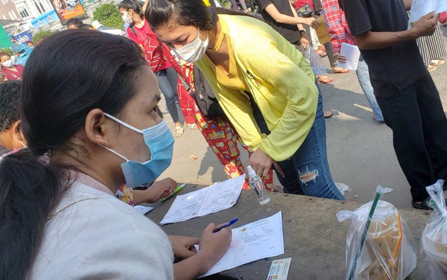Two women fill out Covid-19 vaccine forms at the entrance to the vaccine station at Phnom Penh's Stung Meanchey primary school on May 11, 2021. (Danielle Keeton-Olsen/VOD)