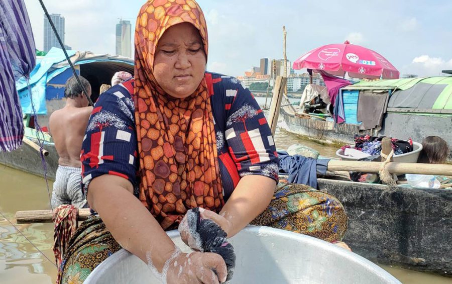 Sakiros, 40, washes her family's clothes after their boat submerged, in Phnom Penh's Chroy Changvar commune on May 18, 2021. (Danielle Keeton-Olsen/VOD)