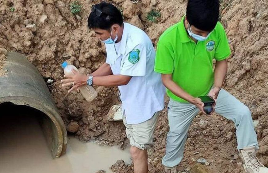 Environmental officials sample water from the Sangke river outside the Phoenix Industrial medical manufacturing plant in Battambang's Treng commune, in a photo posted to the Information Ministry website on May 26, 2021.