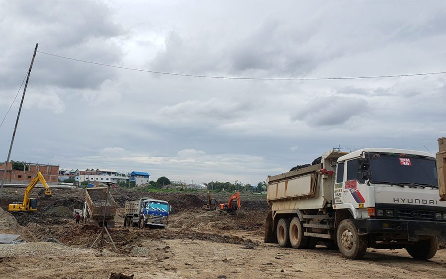 Three dump trucks and three excavators dig out the future reservoir in Boeng Tompun I commune on July 21, 2021. (Danielle Keeton-Olsen/VOD)