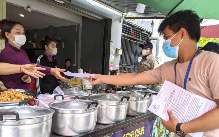A local official hands papers explaining measures to close down dine-in at restaurants to food vendors near Phnom Penh’s Phsar Kabko, on July 30, 2021. (Keat Soriththeavy/VOD)