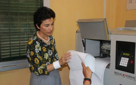 Former French Ambassador Eva Nguyen Binh examines pages printed from a Braille printer at the Institute for Special Education for Deaf and Blind Children in Phnom Penh, in a photo posted to NGO Krousar Thmey's Facebook page on July 28, 2017.