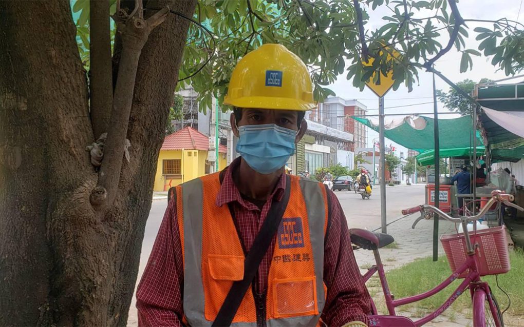 Chuon Vanny, 50, a subcontracted bricklayer wearing CSCEC gear from a previous worksite, said he's still owed money from contractors above him at the Royal Condominium construction project. (Danielle Keeton-Olsen/VOD)