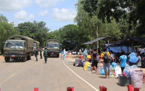 Migrant workers wait at a border checkpoint while military trucks pass in a photo posted to the Banteay Meanchey provincial administration's Facebook page on August 13, 2021.