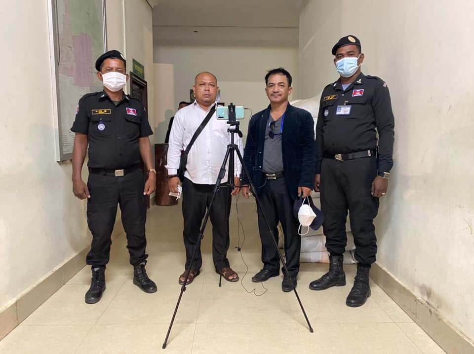 Journalists Sin Lot, 39, and Panh Phalla, 37, stand with police in a photo taken on August 30, 2021. (Provided)