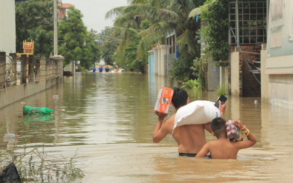 People carry groceries through flooded roads in Phnom Penh’s Dangkao district on October 28, 2021. (Andrew Haffner/VOD)