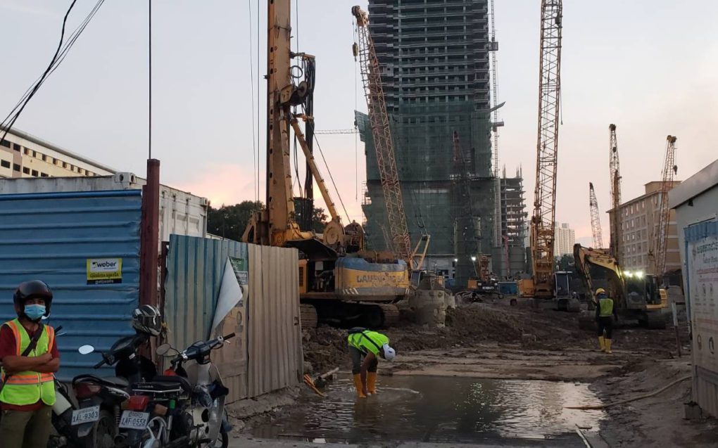 A construction worker washes his rubber boots in a puddle in front of the Naga 3 construction site on October 28, 2021. (Danielle Keeton-Olsen/VOD)