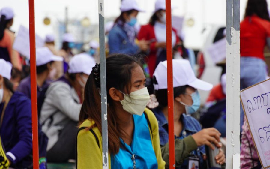 A woman wearing a mask sits behind police barricades during the strike against Nagaworld on December 19, 2021. (Tran Techseng/VOD)