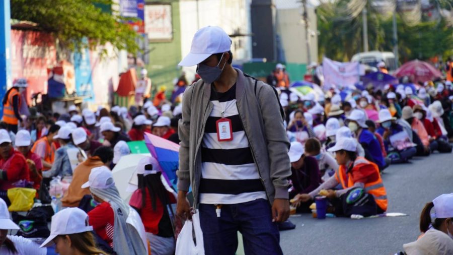 A NagaWorld strike participant walks among seated strikers on the one month anniversary of their strike against the company's violations of labor rights on January 18, 2022. (Tran Techseng/VOD)