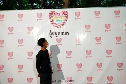 Kamsort, 23, stands in front of a signboard for an event in Phnom Penh from the organization Rainbow Community Kampuchea, where he said he found acceptance in the LGBTQ+ community. (Provided)