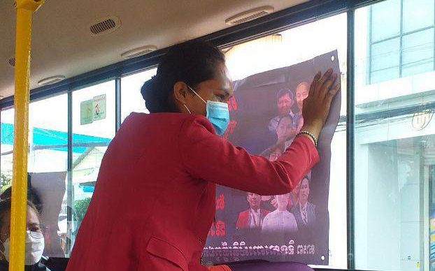 A strike participant disputing NagaWorld casino holds a poster to the window of a bus after strikers were once again rounded up by authorities and driven around the city on March 22, 2022. (Ros Lyheng)