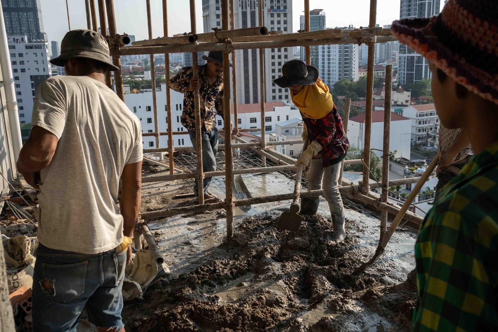 Construction workers lay concrete on the eighth floor of the Bassac Lane site in Phnom Penh. (Andy Ball)
