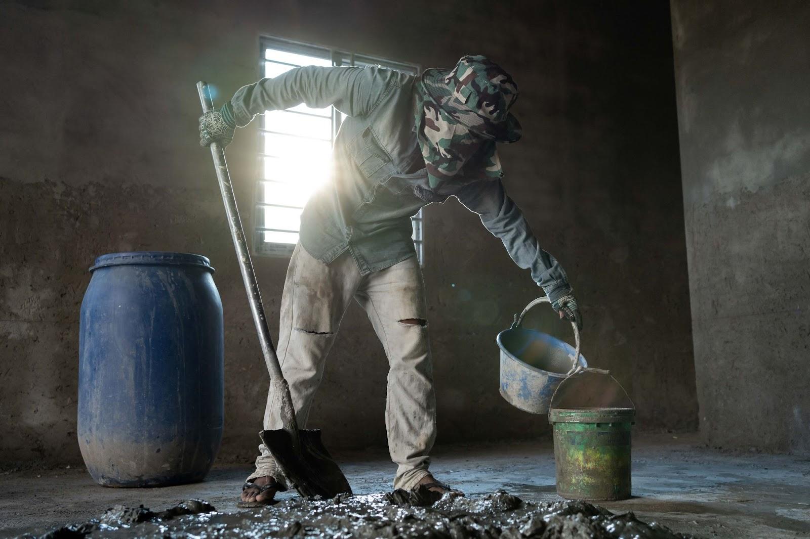 Construction worker Dieb Phearum mixes cement at a construction site on the outskirts of Phnom Penh in Kambol District. (Andy Ball)