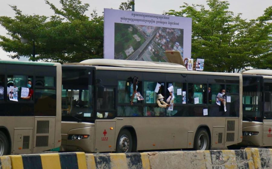 NagaWorld workers hold posters from the windows and roof of the buses their were being held in at the new Freedom Park in Russei Keo district on March 18, 2022.