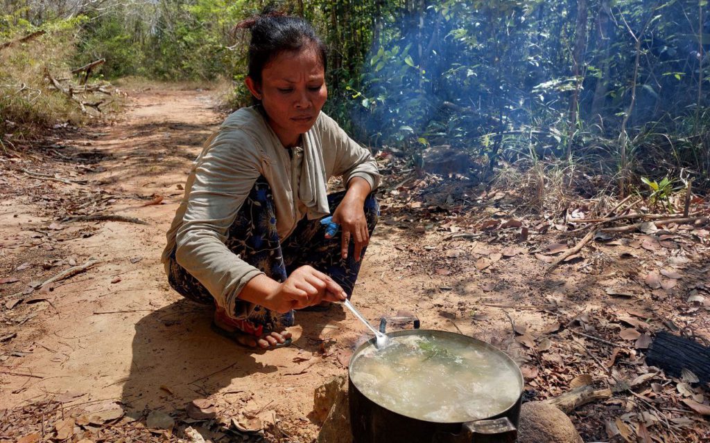 A woman squats to make soup on a campfire in Kratie's Kampong Kbeoung community forest in February 2022. (Keat Soriththeavy/VOD)