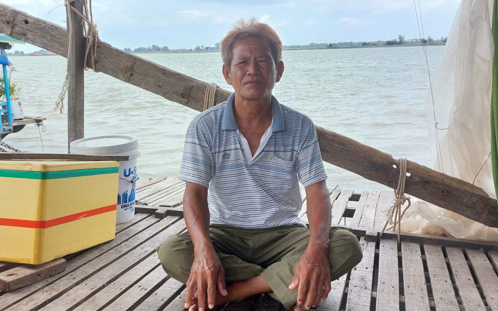 Meng Yeang Tong, 55, sits on his dai with the Mekong river behind him, in Kandal's Ka'am Samnor commune on March 14, 2022. 