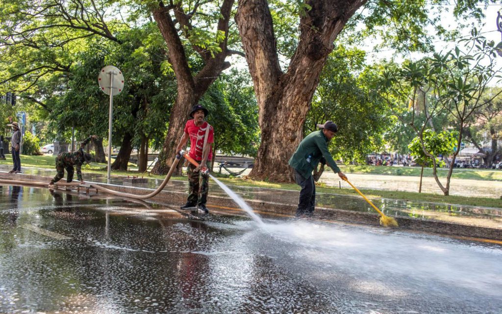 One worker hoses down a street in Siem Reap city while another pushes water away with a broom in preparation for the Sangran festival on March 31, 2022. (Roun Ry/VOD)