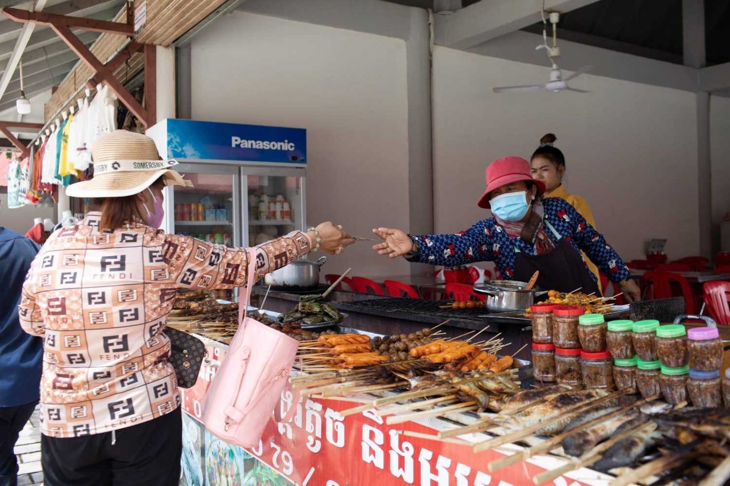Hok Sothea collects money from a customer at her grilled meat and chicken stall in the new Angkor Archaeological Park retail center on April 1, 2022. (Roun Ry/VOD)