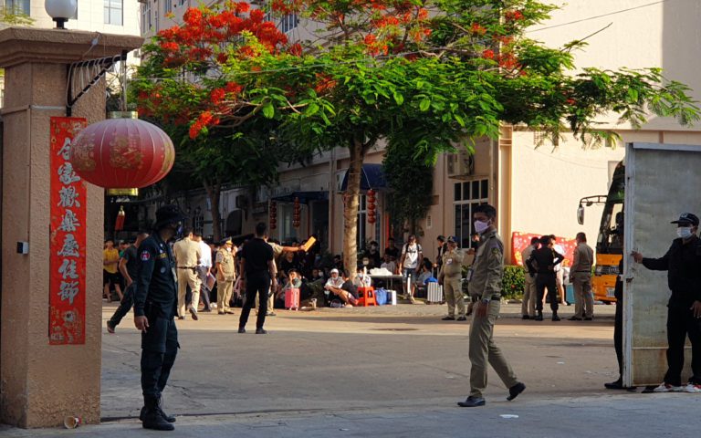 A district guard stands in front of Jin Gang compound, where an operation involving Vietnamese nationals unfolded, in Sihanoukville's Buon commune on April 29, 2022. (Mech Dara/VOD)