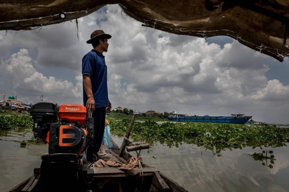Kao Les, a fisherman who lives and works along the Bassac River in Takhmao city, watches the river while standing on a boat on May 11, 2022. (Roun Ry/VOD)
