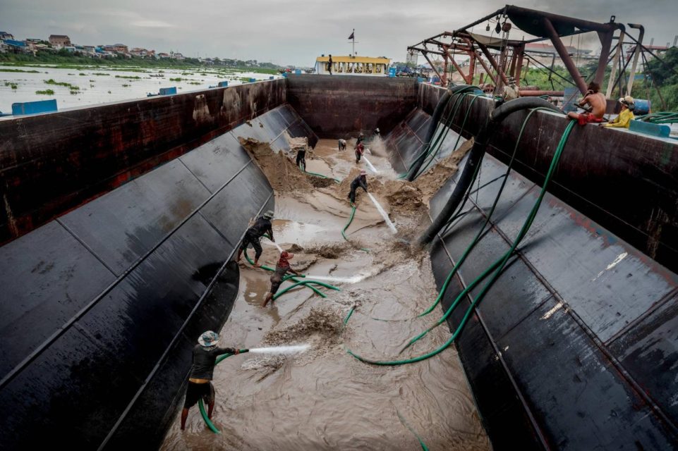 Sand dredging workers use the pressure of water from a hose to push sand into a pipe that will transport it to a sand depot or construction site, in a sand barge in Phnom Penh on May 11, 2022. (Roun Ry/VOD)