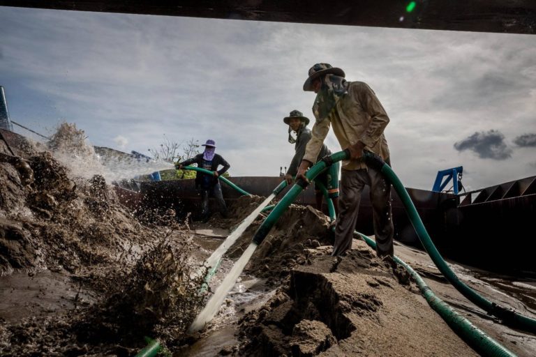 Sand dredging workers use the pressure of water from a hose to push sand into a pipe that will transport it to a sand depot or construction site, in Phnom Penh on May 11, 2022. (Roun Ry/VOD)