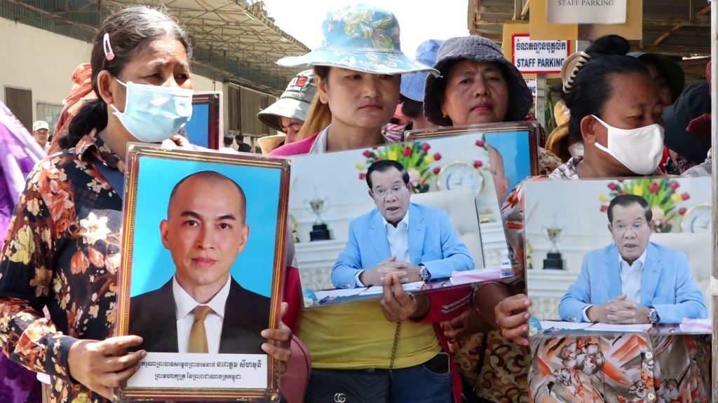 Workers from Canteran Apparel hold pictures of Prime Minister Hun Sen and King Norodom Sihamoni while protesting the factory closure on May 16, 2022. (Hy Chhay/VOD)