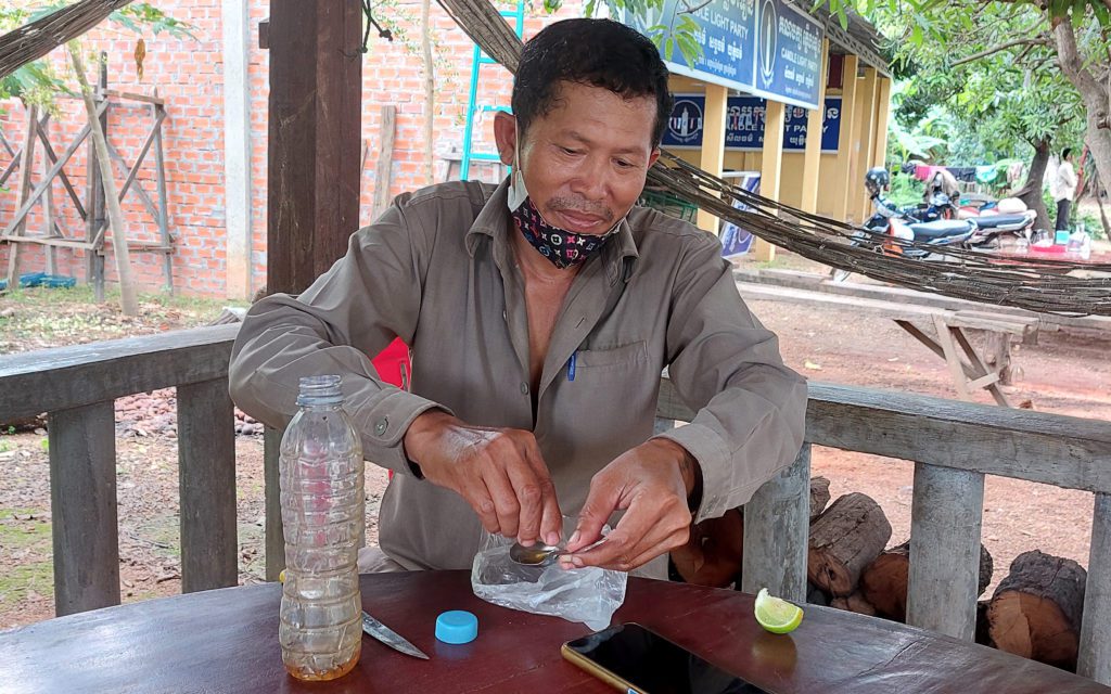 Siek Mekong, former Srekor commune chief and current Candlelight Party candidate, squeezes lime onto a spoonful of remedy to treat illness at the party's headquarters in Stung Treng city on May 20, 2022. (Danielle Keeton-Olsen/VOD)