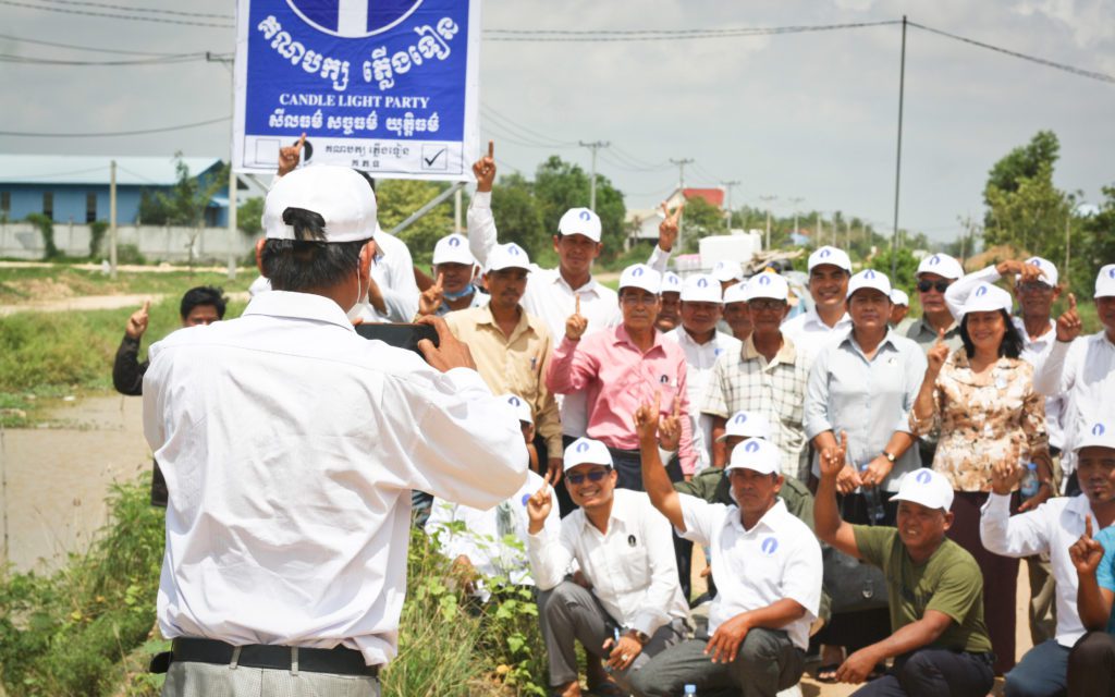 Candlelight Party activists pose for a photo in front of a newly erected party billboard in Kandal province on May 6, 2022. (Michael Dickison/VOD)