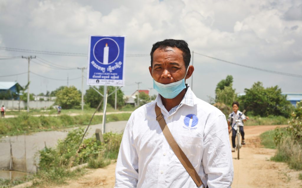 Prek Sleng commune Candlelight Party candidate Kuon Sam Ath stands in front of a newly erected party billboard in Kandal province on May 6, 2022. (Michael Dickison/VOD)