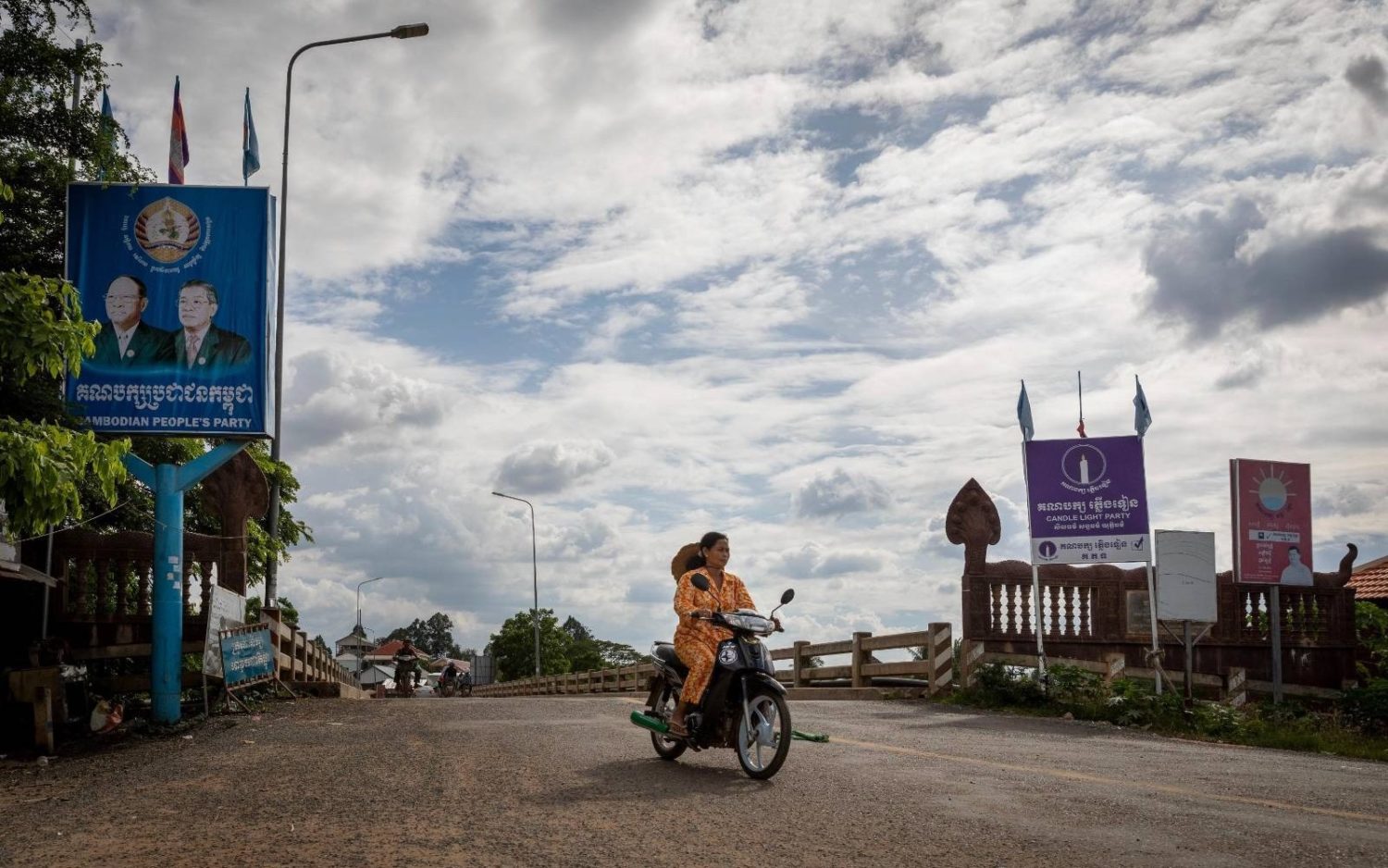 A motorist rides past political party billboards in Kampong Cham province's Sdao commune on May 8, 2022.