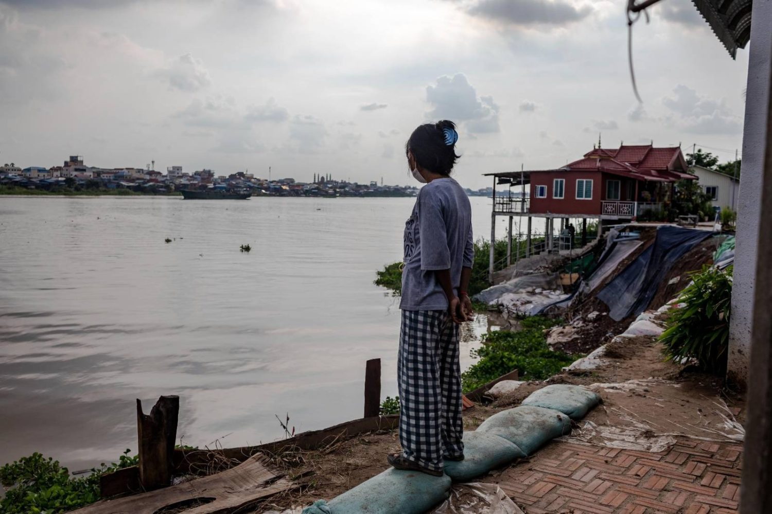 Ros Borany, 34, looks out over a collapsed riverbank in front of her house along the Tonle Sap river in Chroy Changva district's Prek Tasek commune on July 26, 2022. (Roun Ry/VOD)