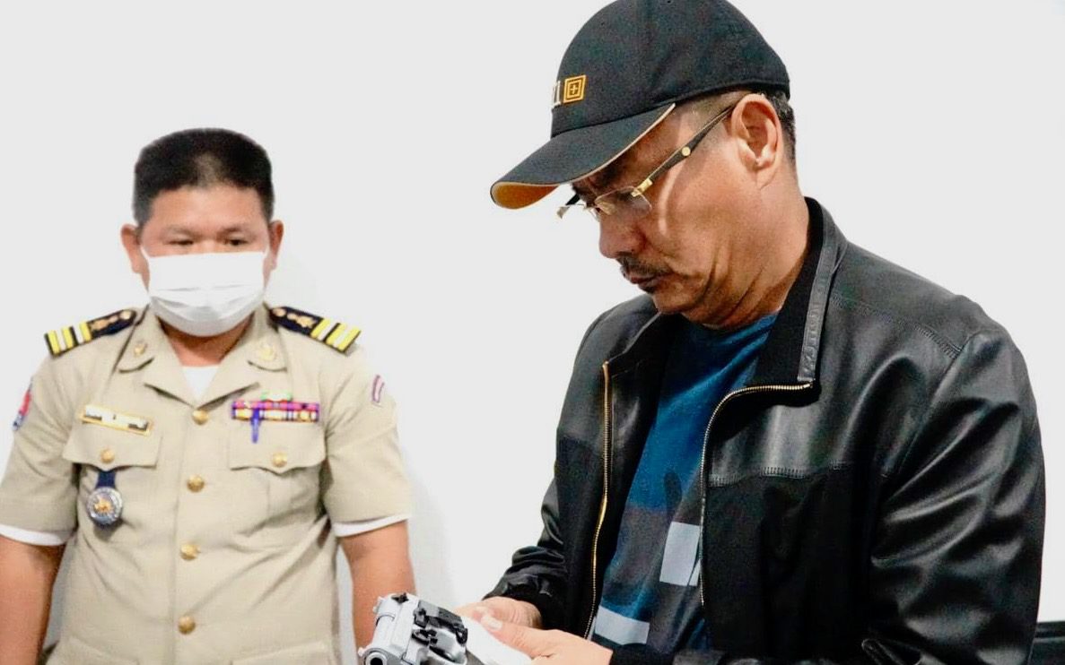 Preah Sihanouk police chief Chuon Narin inspects a gun that was allegedly used in a shooting in June 2022.