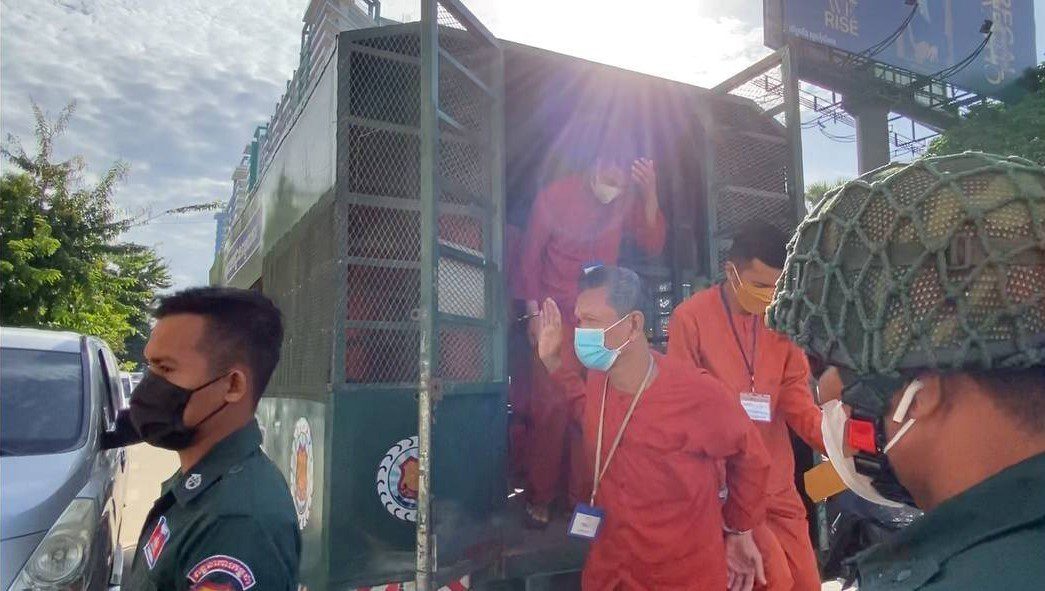 Kampong Chhnang deputy provincial police chief Sum Socheat, at center in the blue mask, exits a prison van to enter Phnom Penh Municipal Court on August 4, 2022. (Supplied)